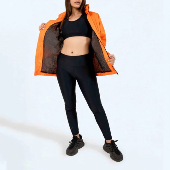Woman wearing an orange jacket over a black sports outfit on a white background in American Market